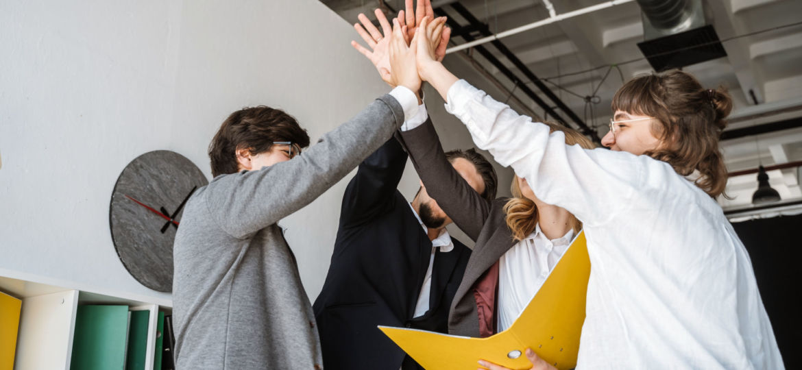 Cheerful young group of people standing in the office and giving high five