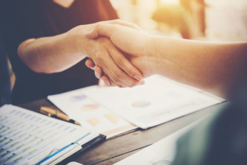 close-up-of-two-business-people-shaking-hands-while-sitting-at-the-working-place-scaled